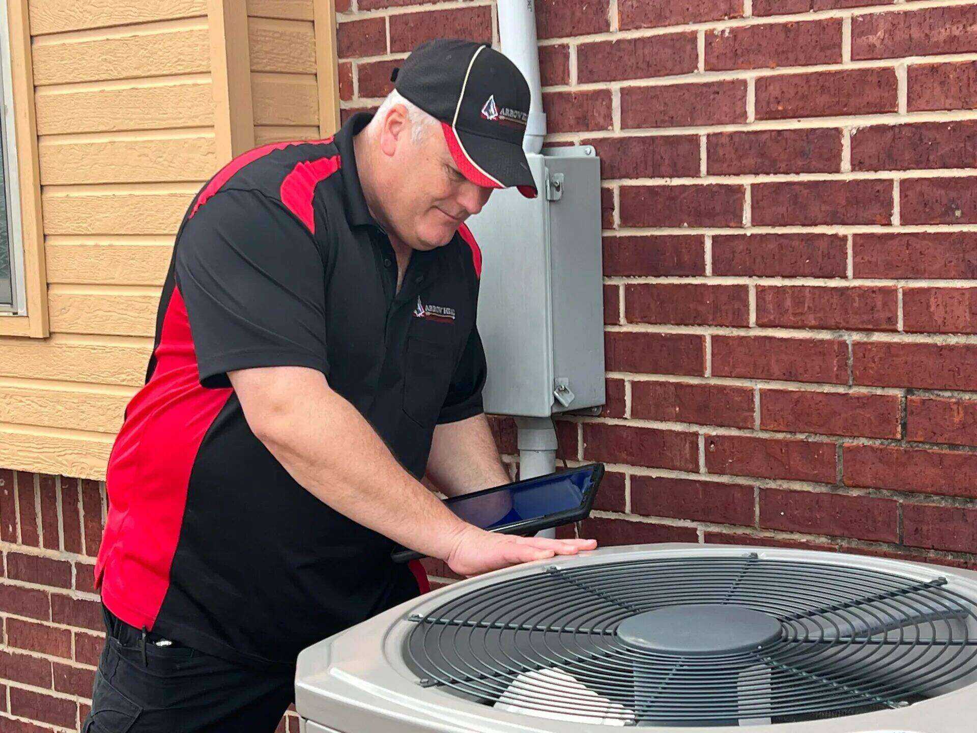 Edward Hagstrom inspecting an outdoor A/C condenser with a tablet