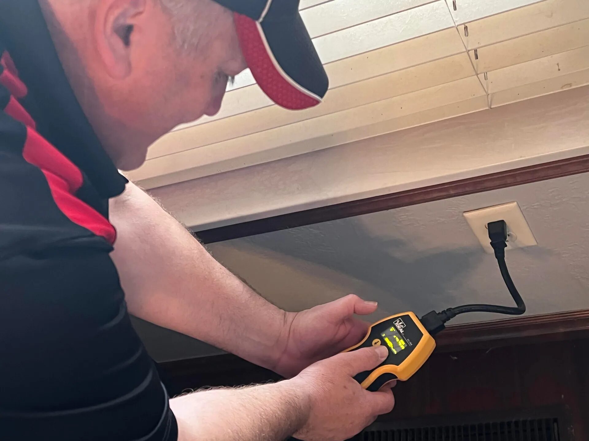 Edward Hagstrom using an electrical tester at a wall outlet